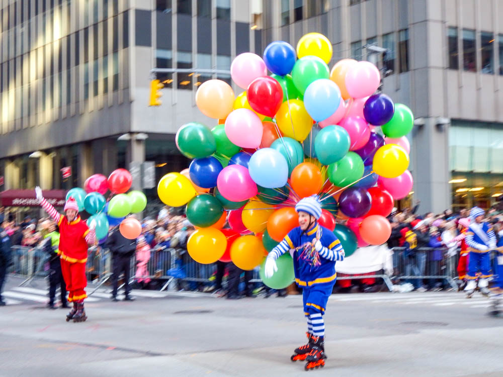 roller-blading clown carrying a hundred balloons