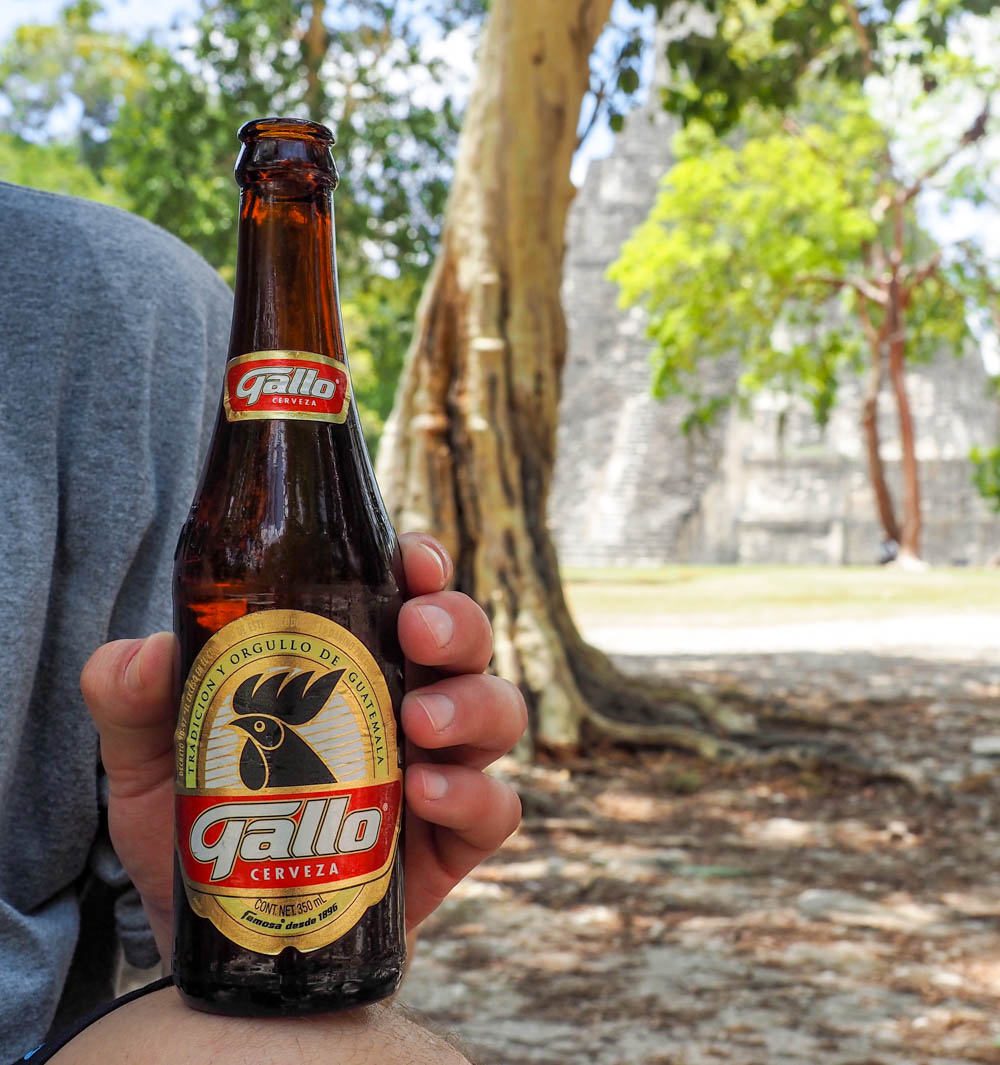 Man holding bottle of Gallo beer in front of ancient temple