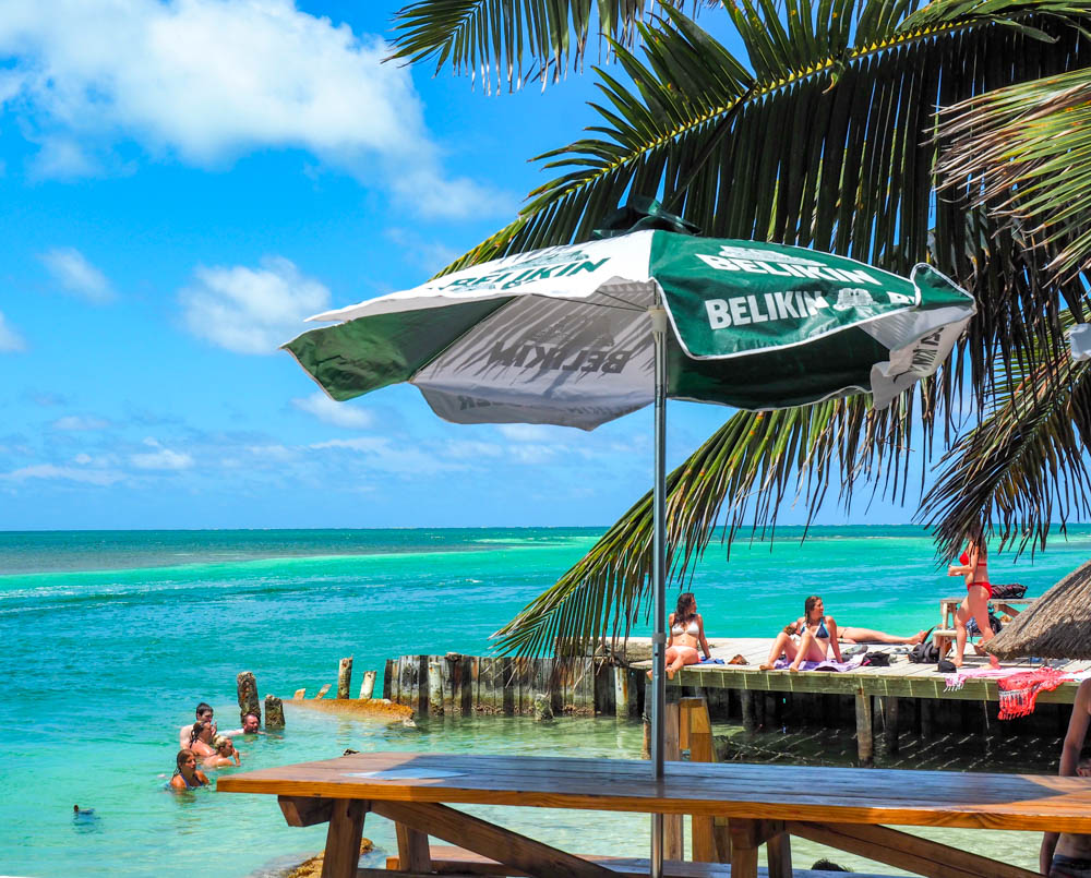 tiki bar next to turquoise ocean water and palm trees