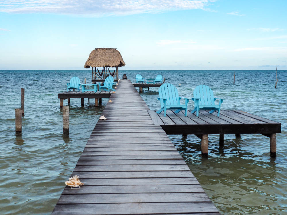 dock over the ocean with light blue chairs and conch shells