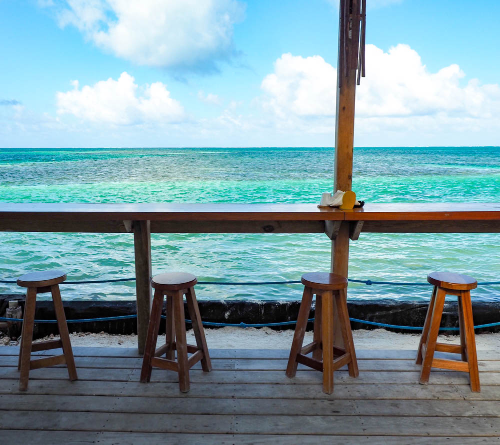 bar and stools in front of a turquoise ocean