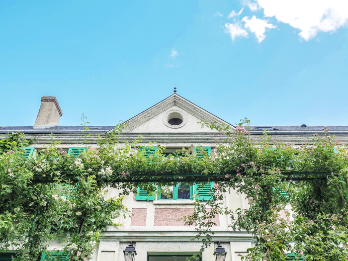 close up of monet's house and a trellis covered in vines