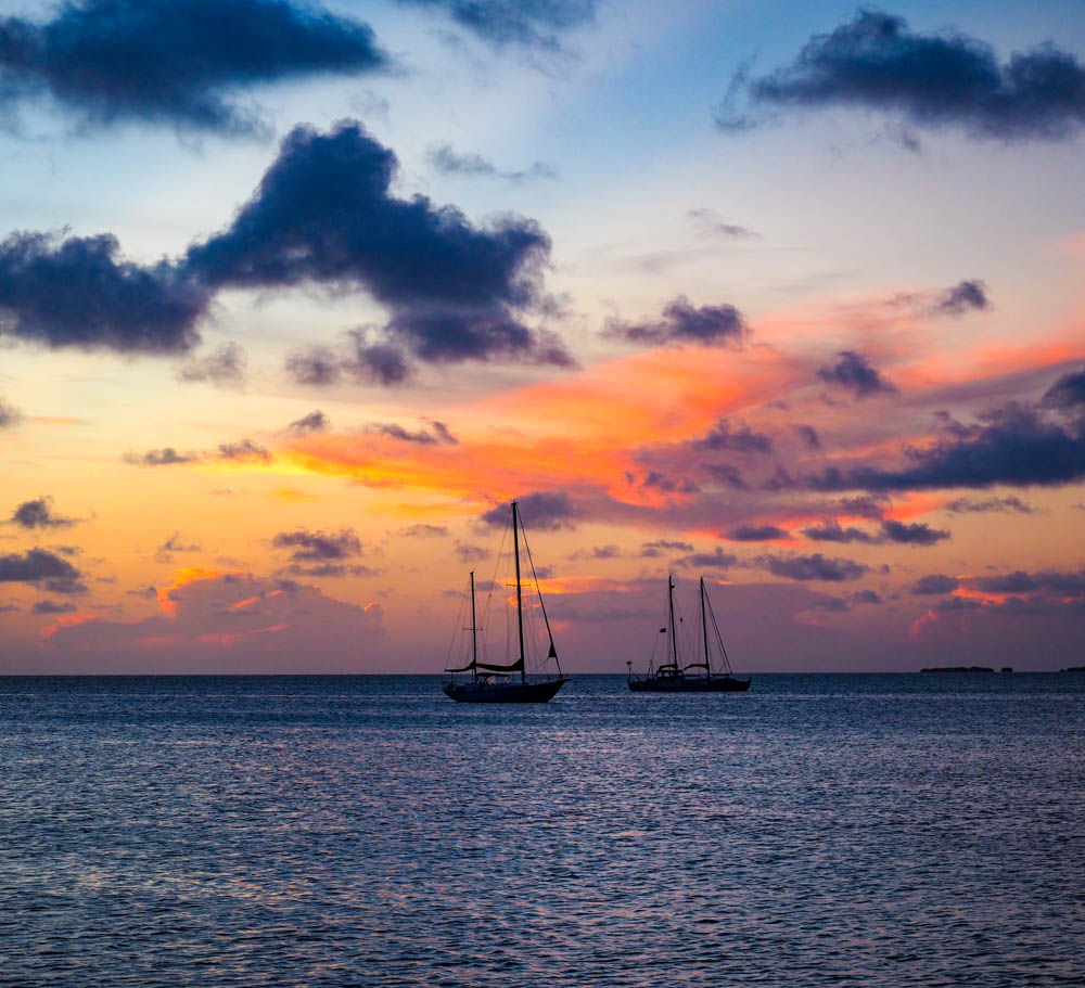 caribbean sunset in caye caulker belize, orange skies sailboats