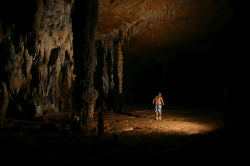 Man with flashlight in the ATM Cave / What to pack for the ATM Cave in Belize: What to wear, what shoes to wear, what to bring, and what to never, ever bring into the ATM Cave.