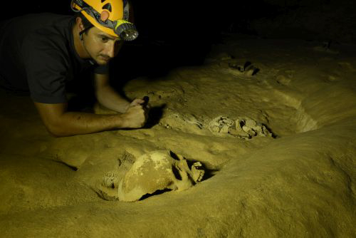 Man wearing a helmet and head lamp inside the ATM Cave / What to pack for the ATM Cave in Belize: What to wear, what shoes to wear, what to bring, and what to never, ever bring into the ATM Cave.