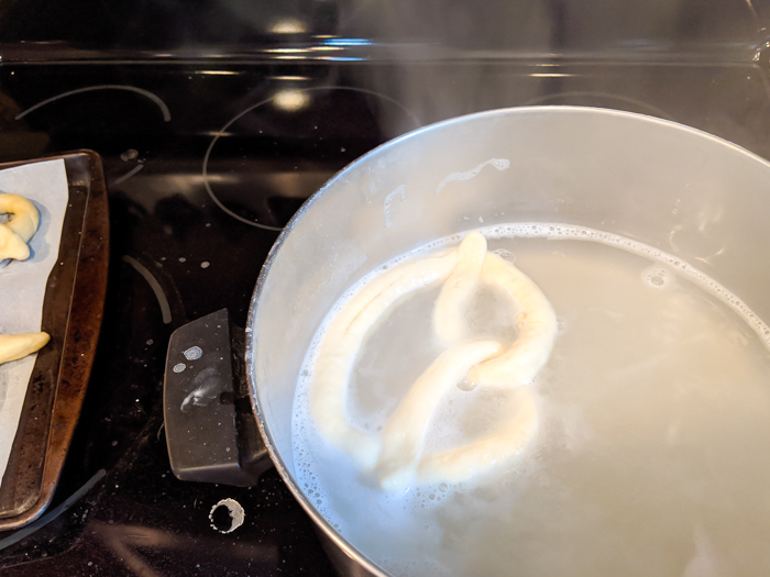 soft pretzel dough floating in a baking soda bath