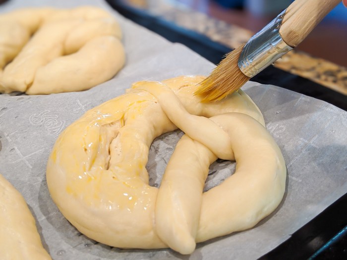 brushing oktoberfest pretzel dough with and egg wash