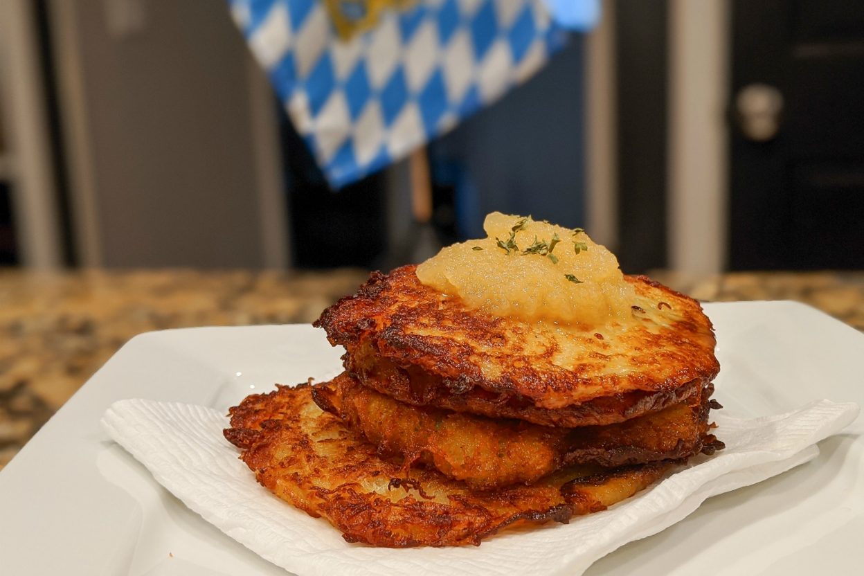 plate of potato pancakes with apple sauce in front of a bavarian flag