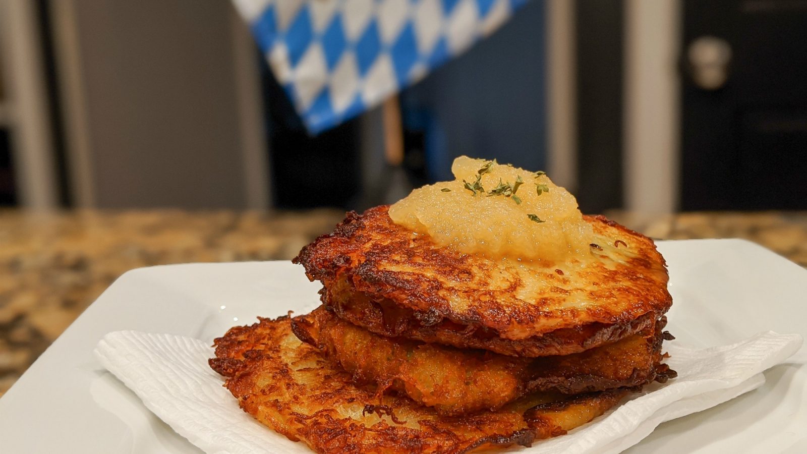 plate of potato pancakes with apple sauce in front of a bavarian flag