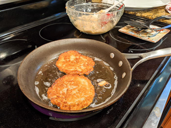 frying potato pancakes in oil on a stovetop