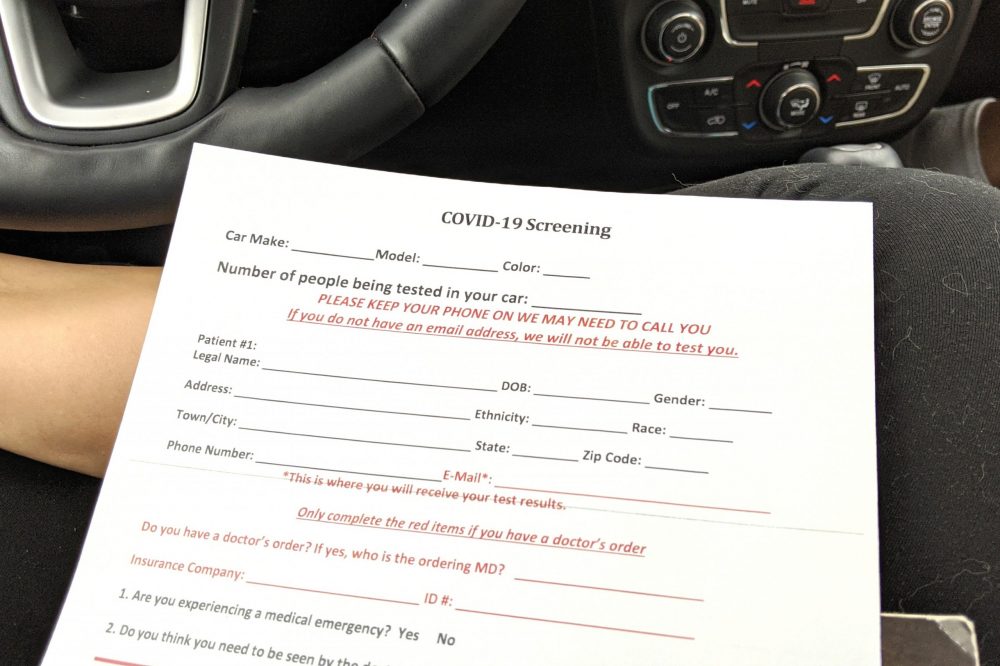 Covid test screening form questionnaire on woman's lap in the car