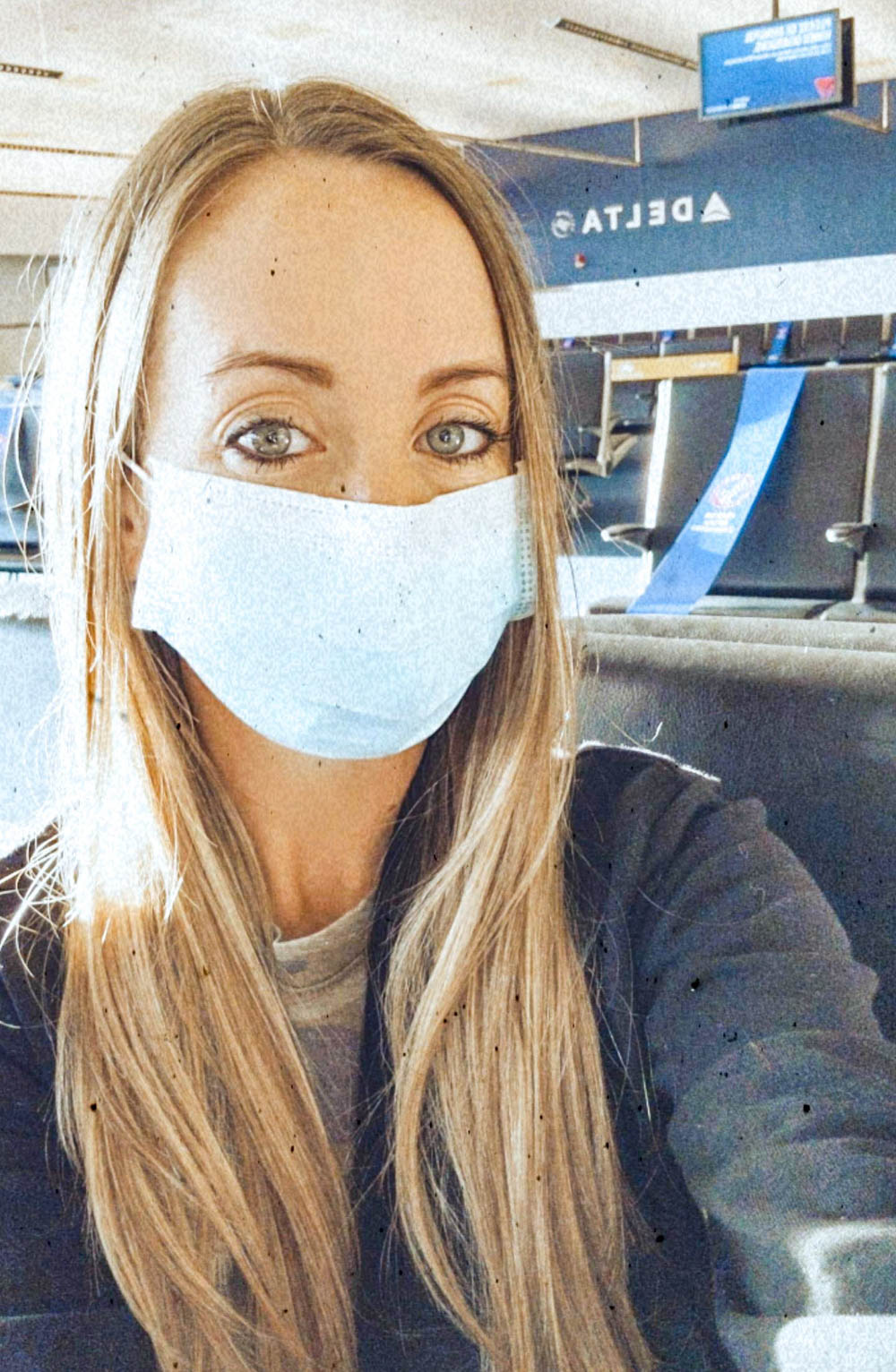 Blonde woman in a mask at the airport traveling during the pandemic