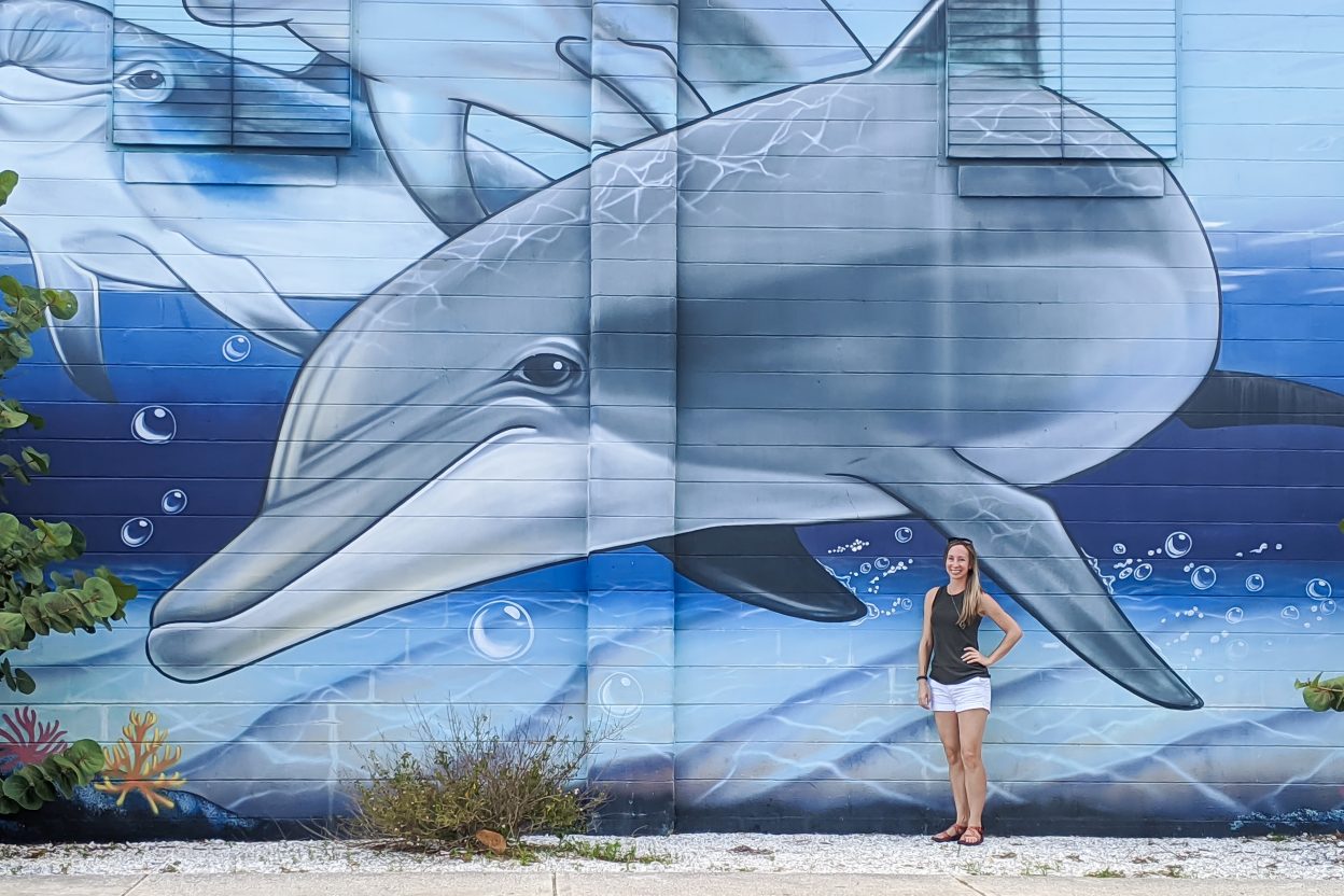 Large dolphin mural and me standing in front of it