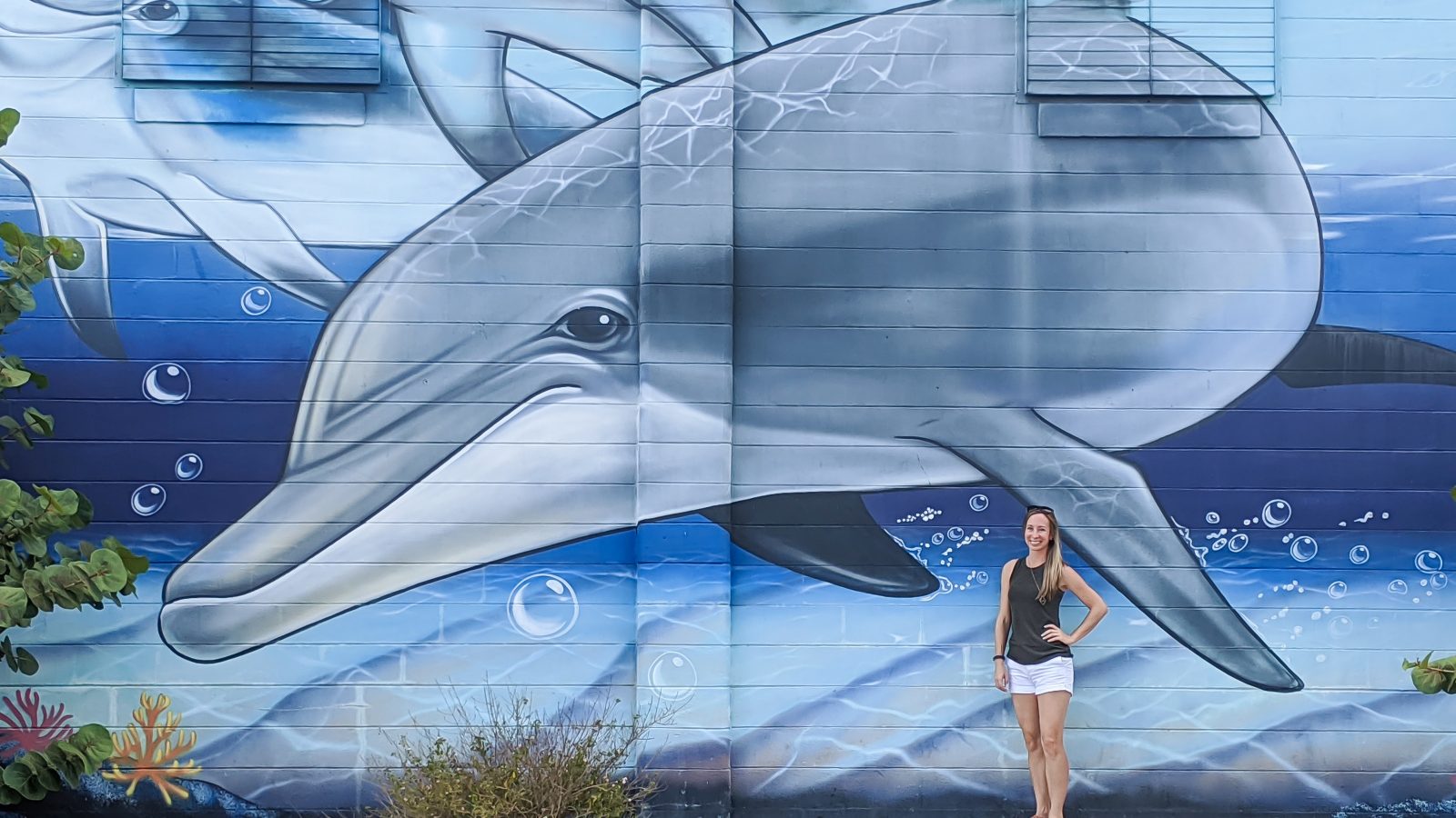 Large dolphin mural and me standing in front of it