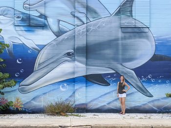 Large dolphin mural and me standing in front of it