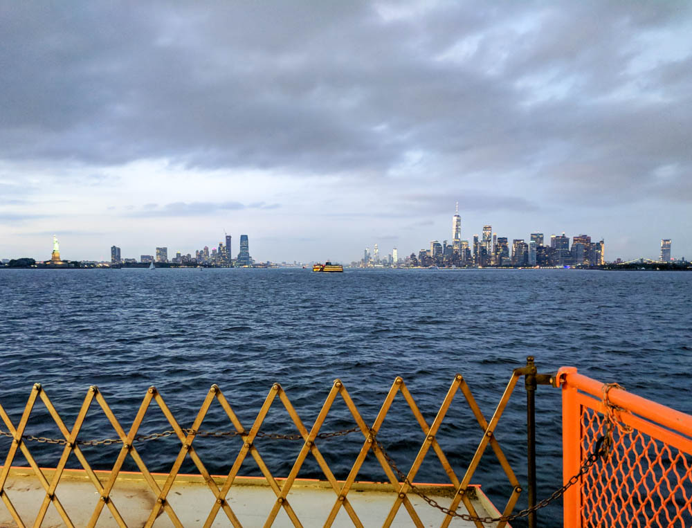 view of manhattan skyline and statue of liberty at dusk from the staten island ferry