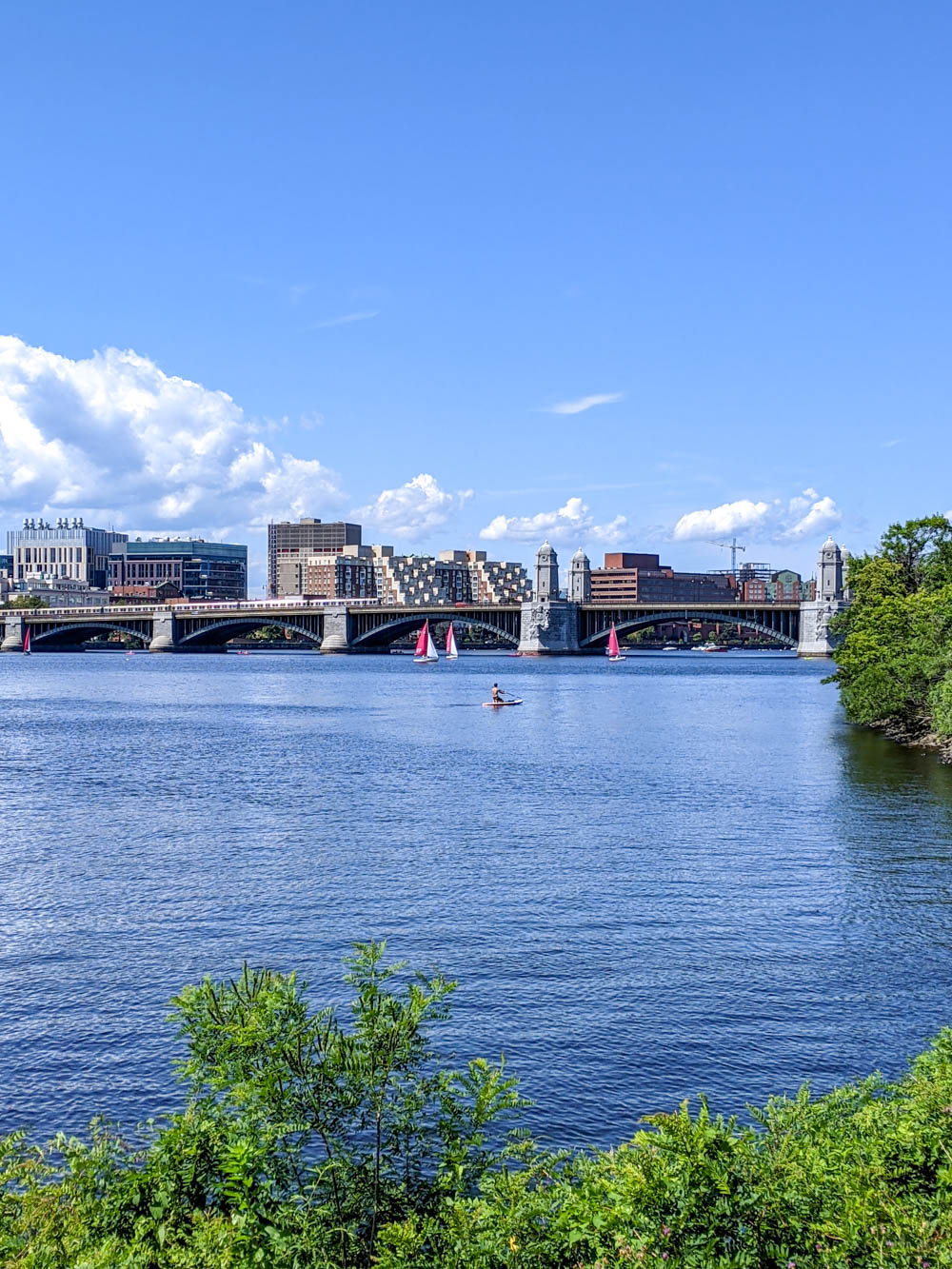 man on a paddleboard in front of boston skyline