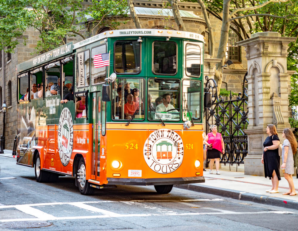 Green and orange Old Town Trolley Tour Bus driving through Boston