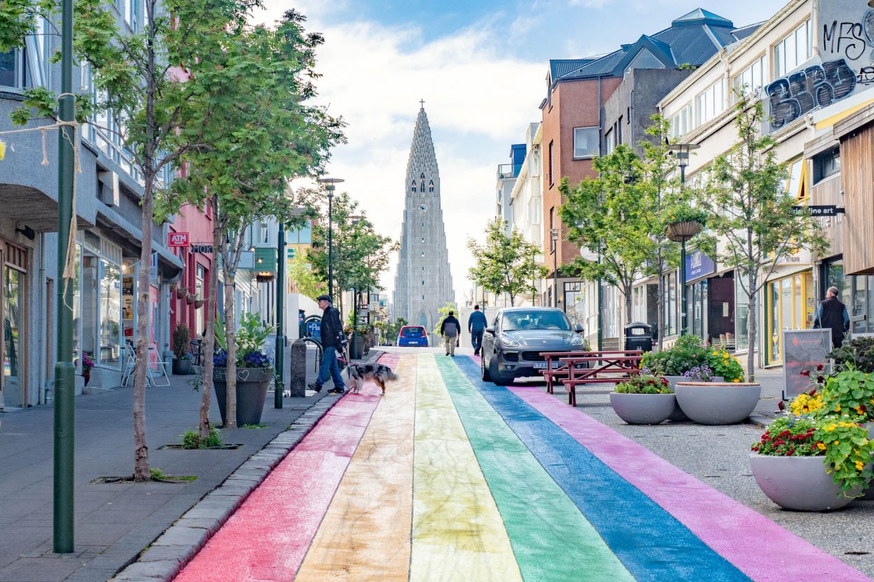 City street painted like a rainbow with a tall church at the end