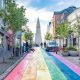 City street painted like a rainbow with a tall church at the end