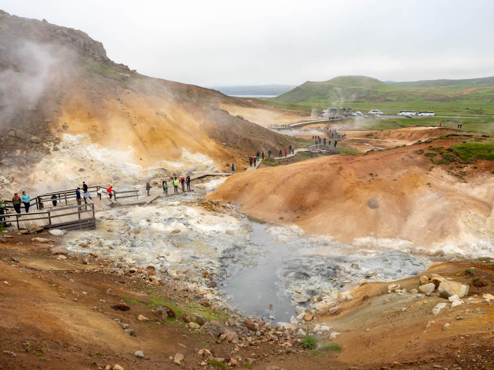 brown and white geothermal pools emitting steam