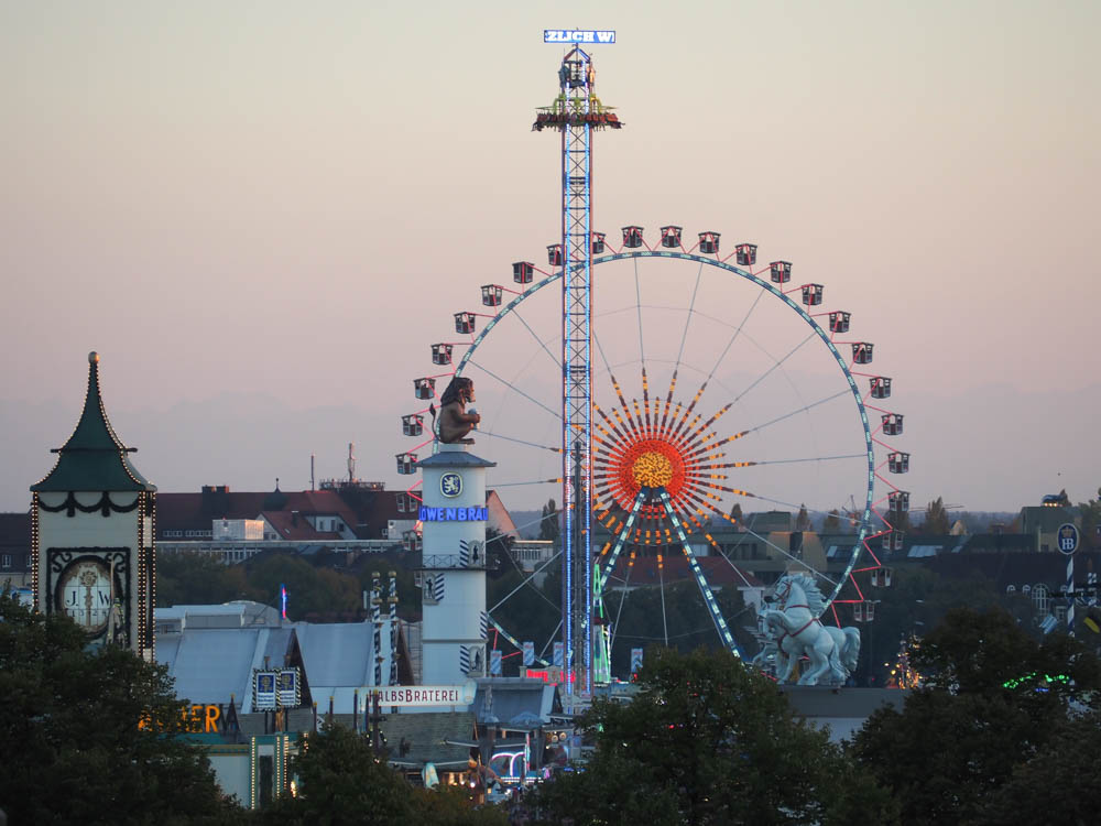 oktoberfest beer tents and ferris wheel at dusk from afar