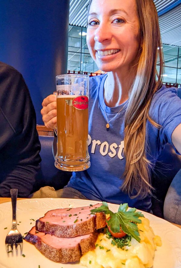 Girl in shirt that says Prost! on the front holding up a beer