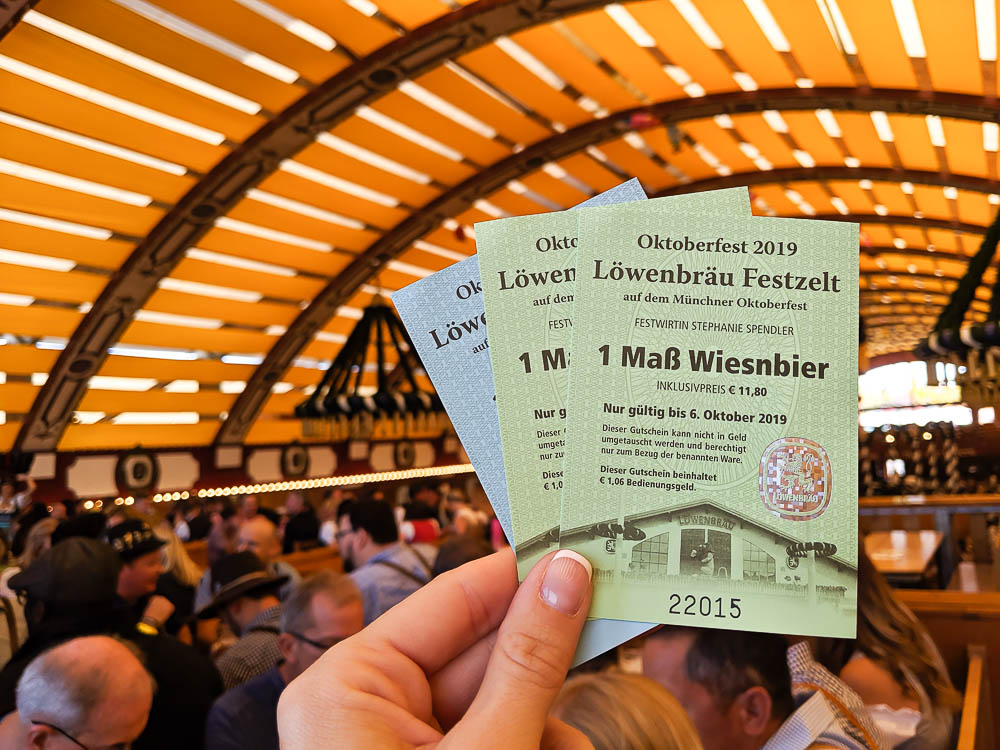 hand holding up green and blue beer tent vouchers inside a beer tent