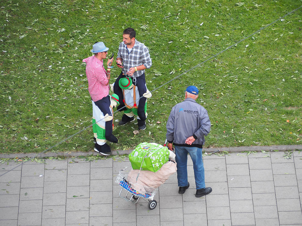 two guys in halloween costumes on the sidewalk while an older man stares at them