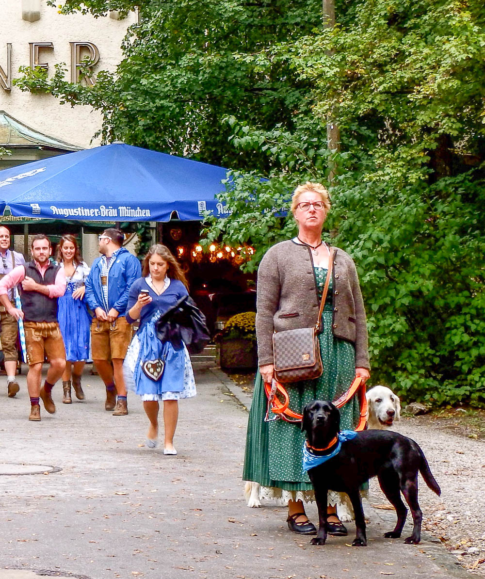 woman in traditional oktoberfest clothing walking her two dogs
