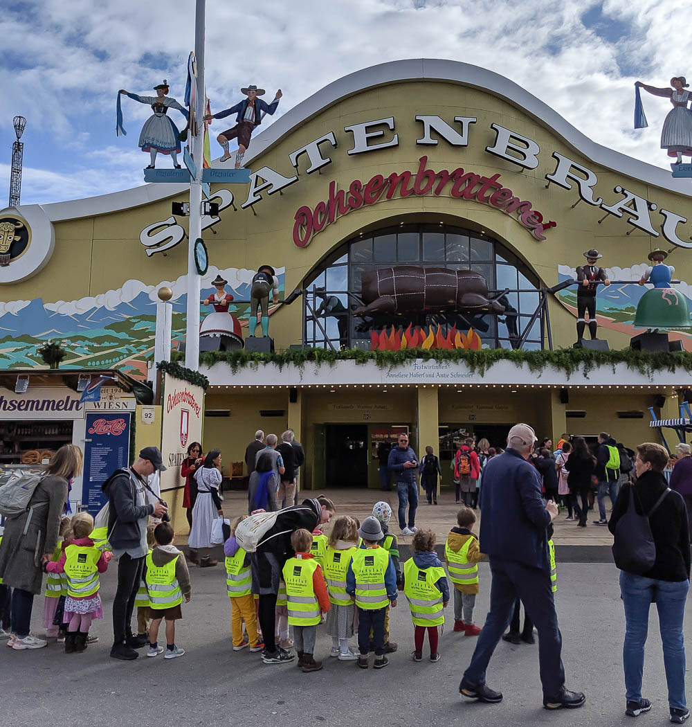 group of children in yellow vests outside an oktoberfest beer tent