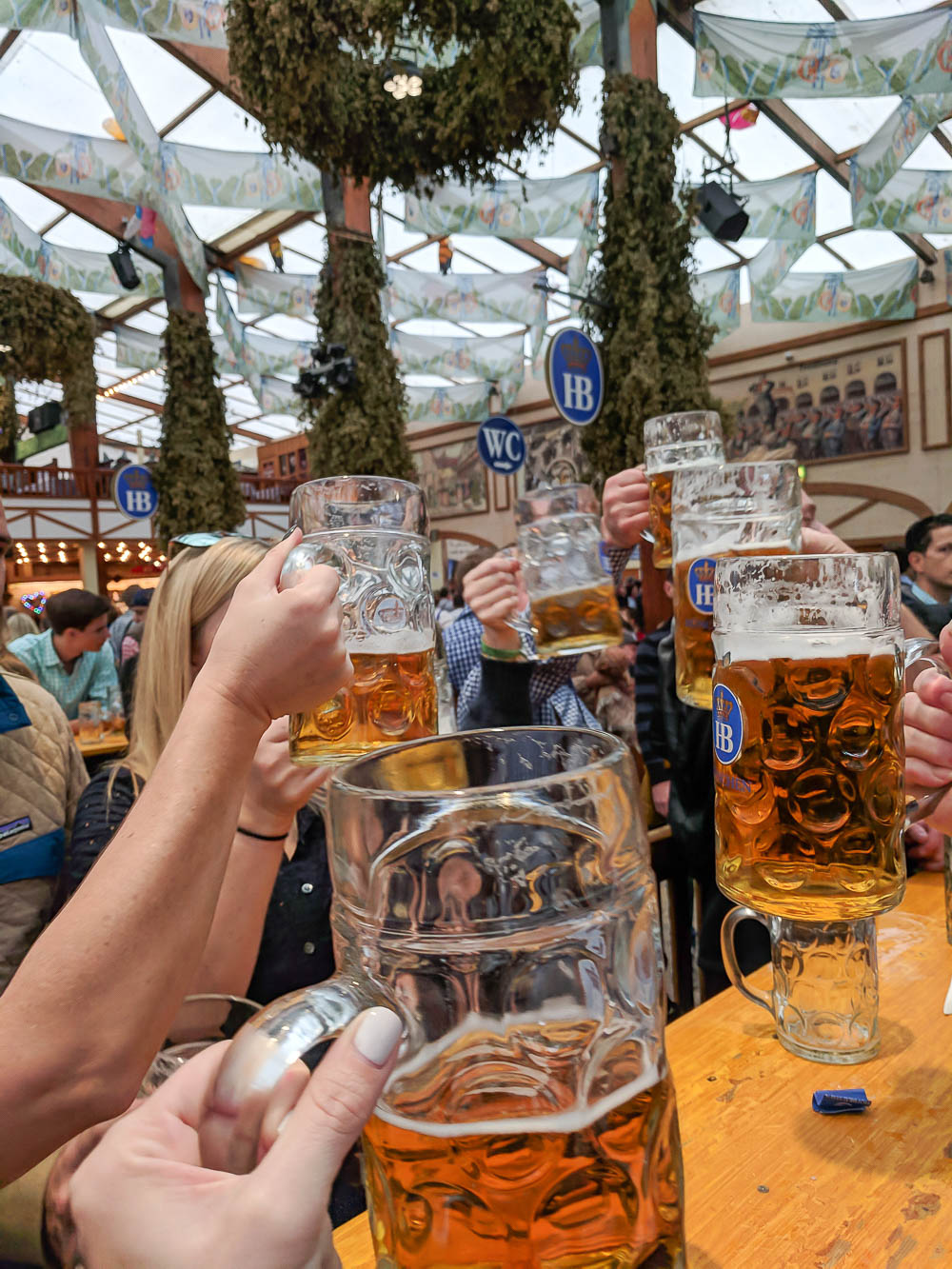 group of people all hoisting their liter beers at oktoberfest