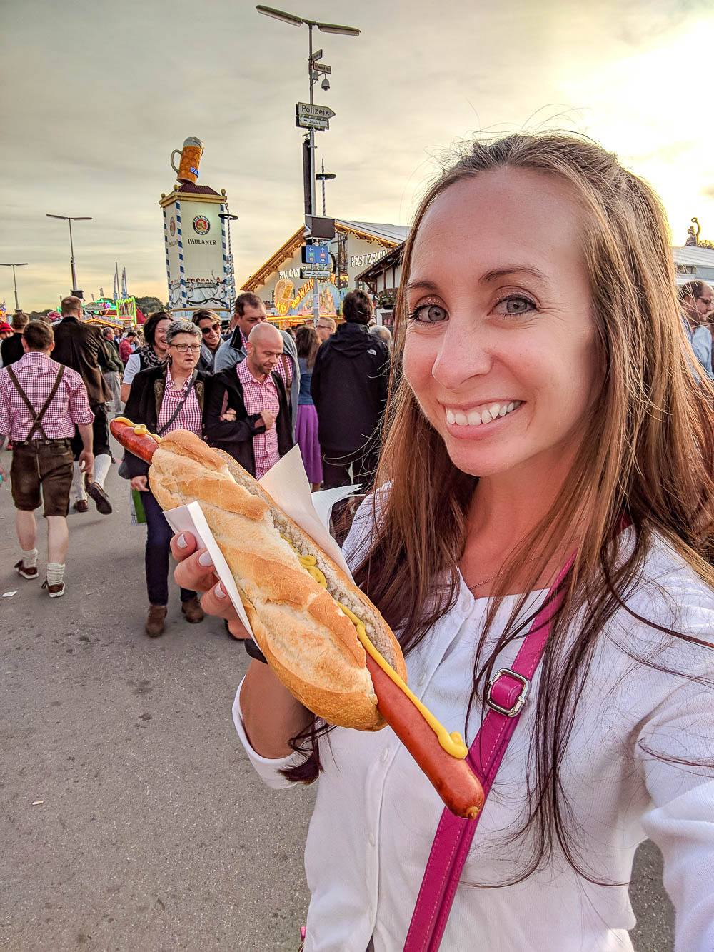 me in a white sweater at oktoberfest holding up a long sausage