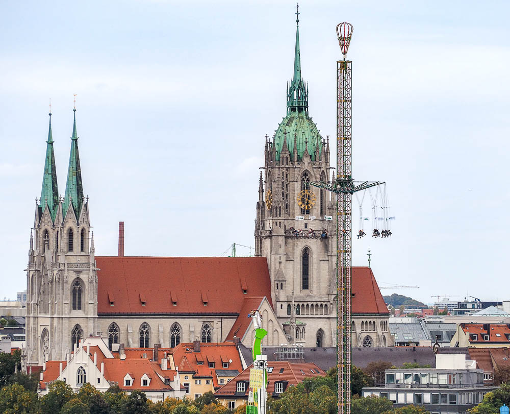 gothic church with oktoberfest rides in front of it