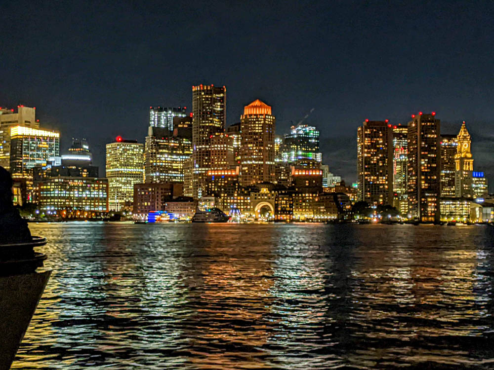 Boston skyline at night as seen from a boat on the water
