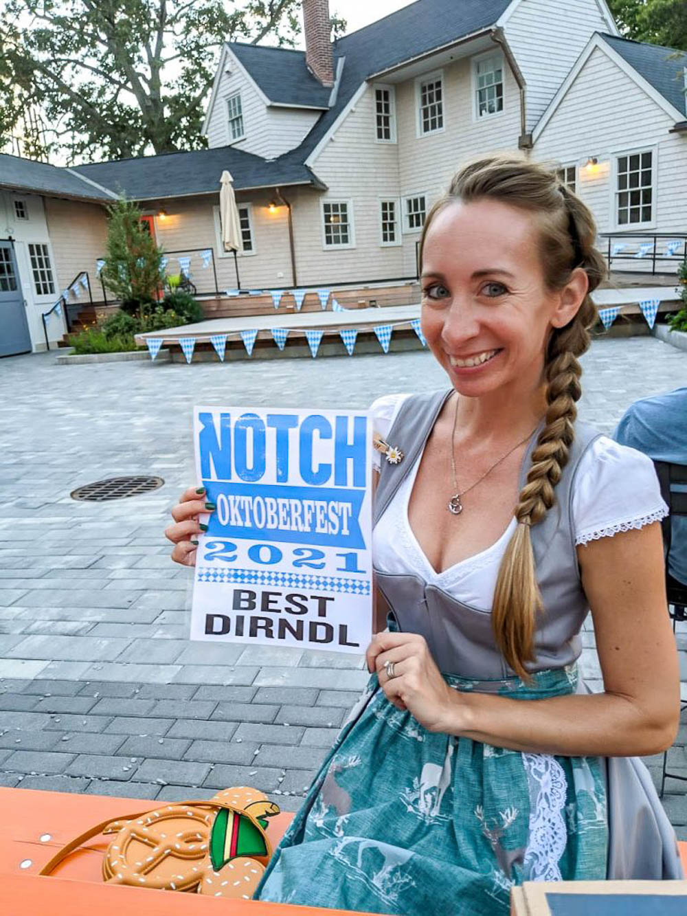 me in a gray dirndl and braid holding a sign that says best dirndl