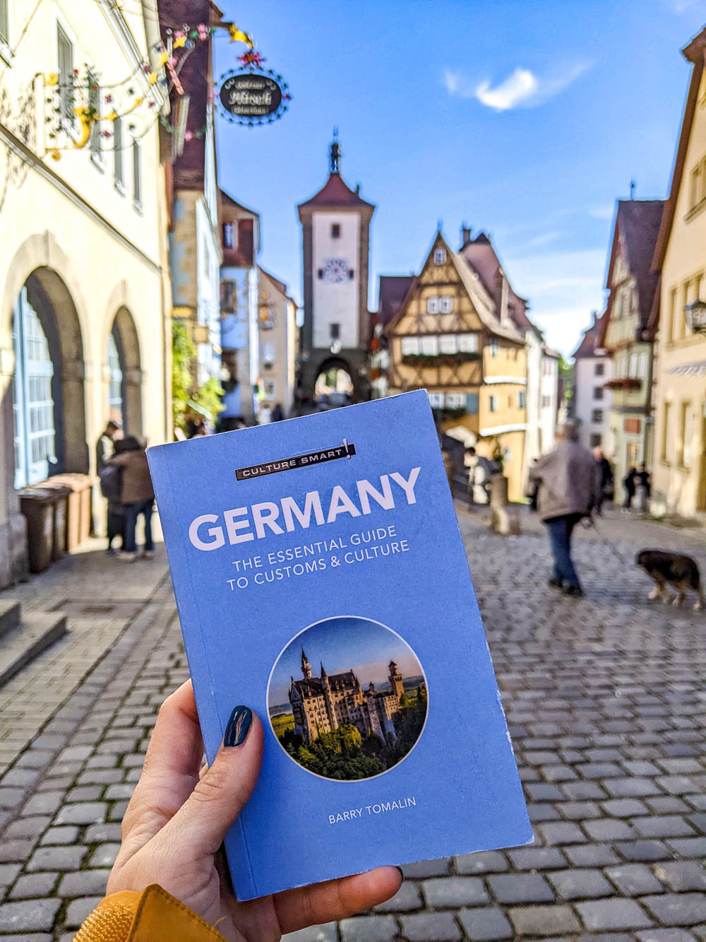 hand holding up small germany guidebook in front of cute houses