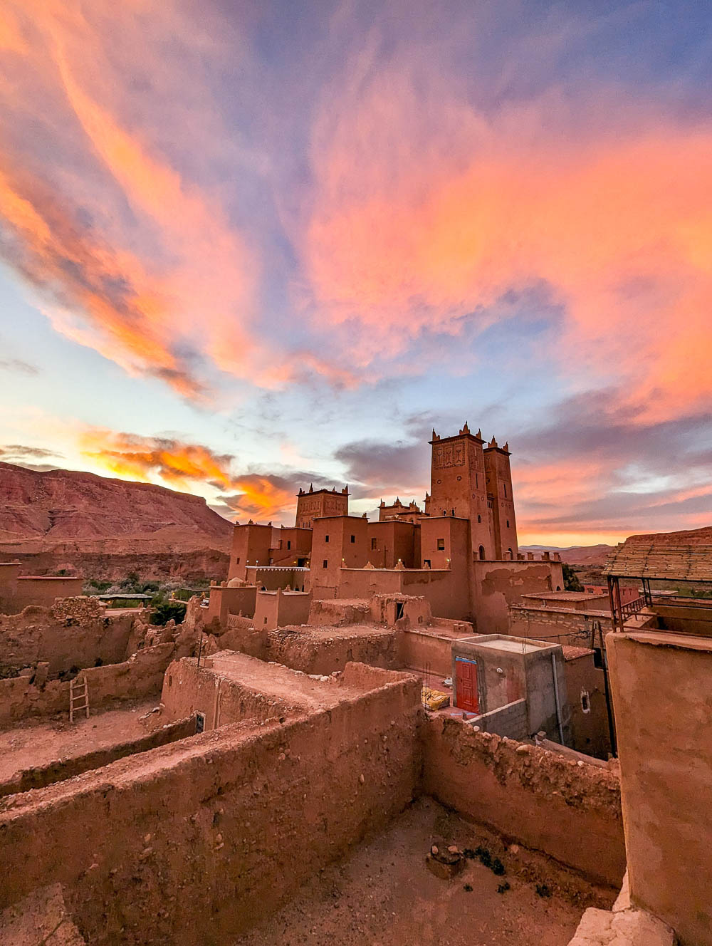 brightly colored sunset above a brown sandcastle looking building