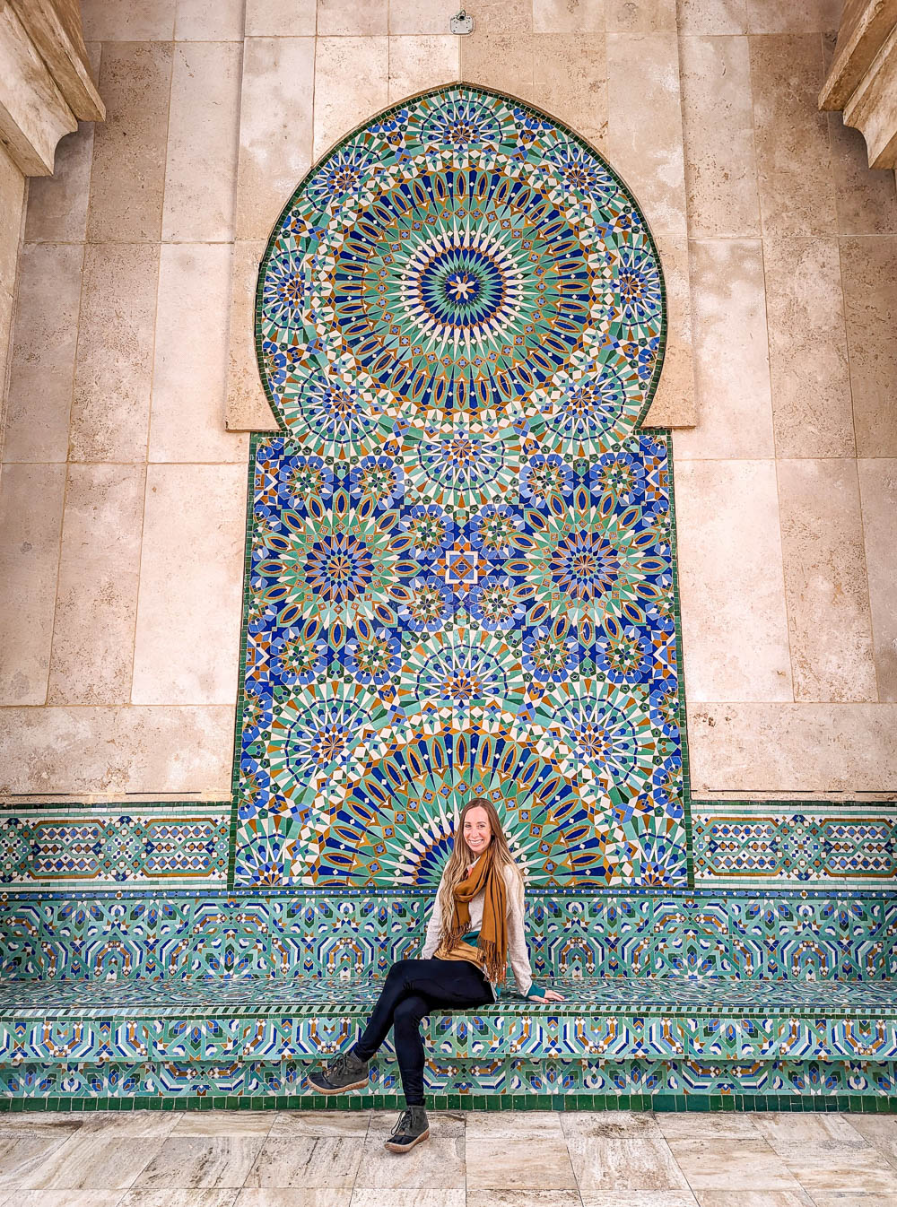tiny woman sitting in front of a large green mosaic