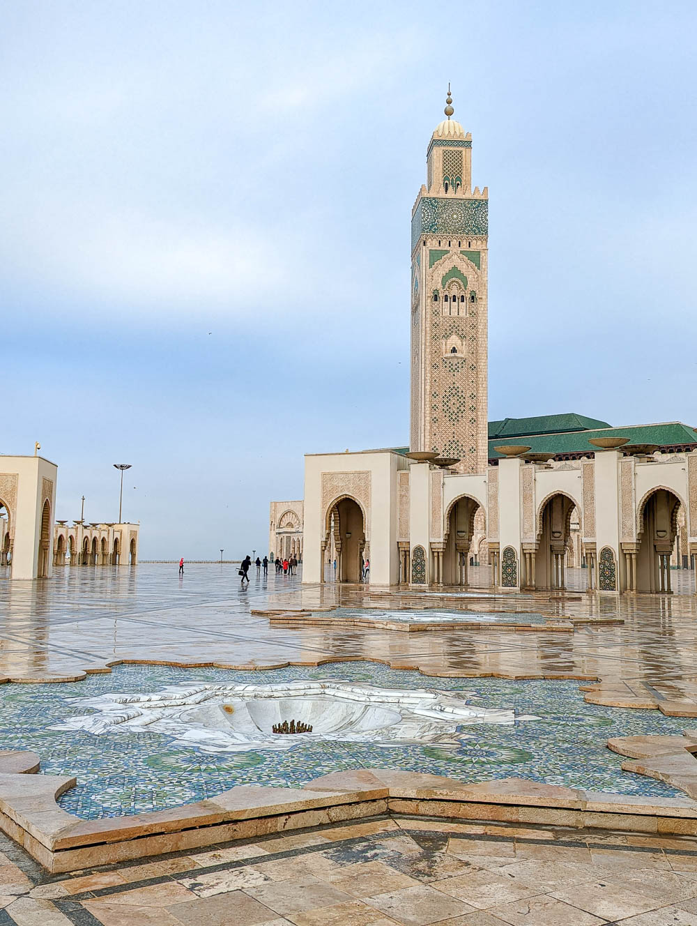 tall tan and green minaret behind a star shaped fountain