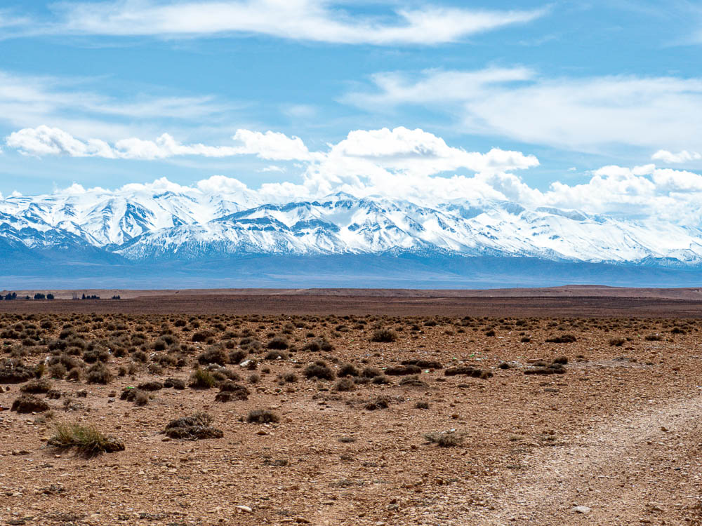 huge snowy mountains at the end of a dirt road