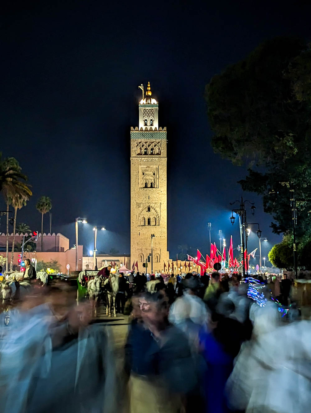 tall brown mosque at night with lots of movement in front