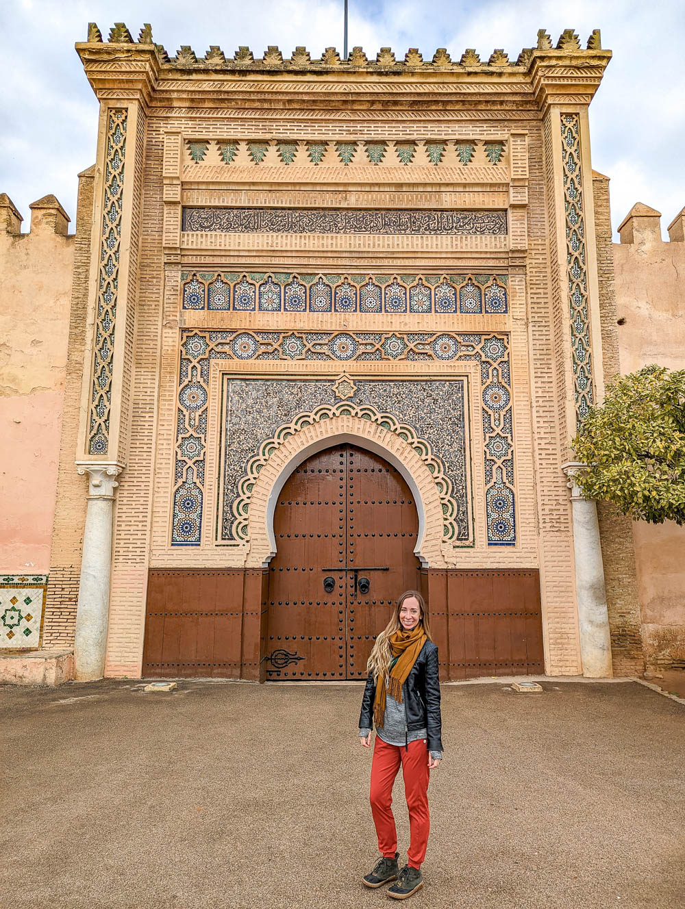 woman in red pants standing in front of a large door