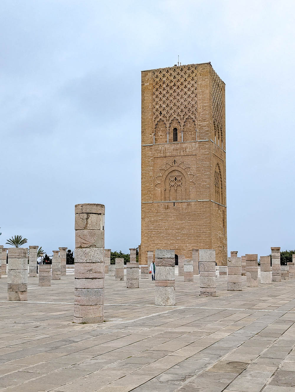 tall brown minaret in front of ruined columns