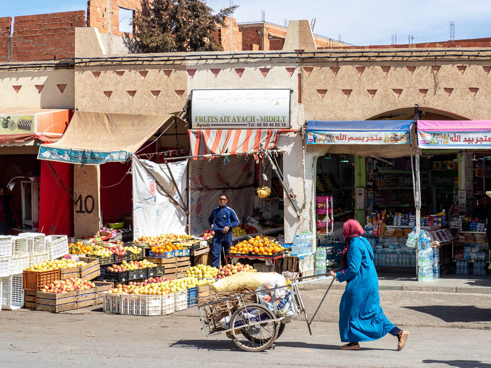 woman pushing a cart in front of a store selling apples