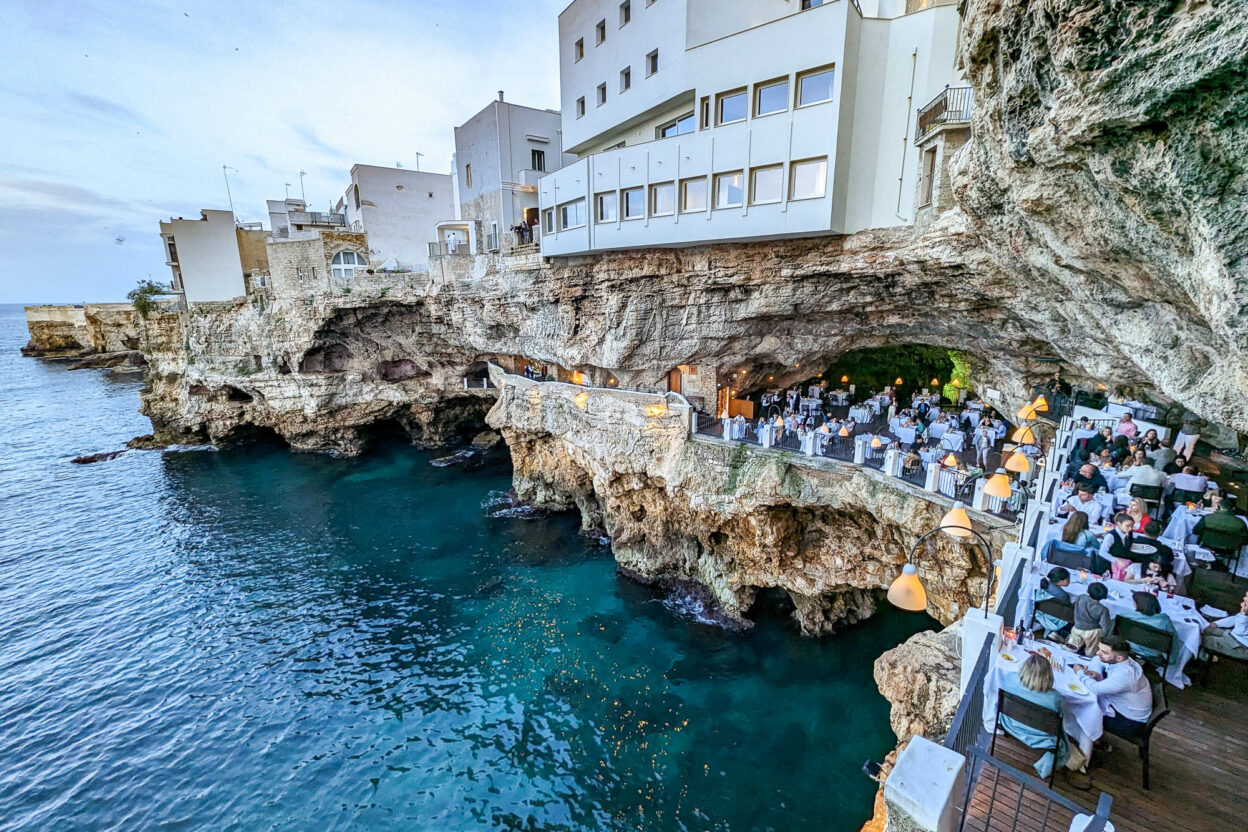 looking down on the tables and sea from above inside the cave during the day