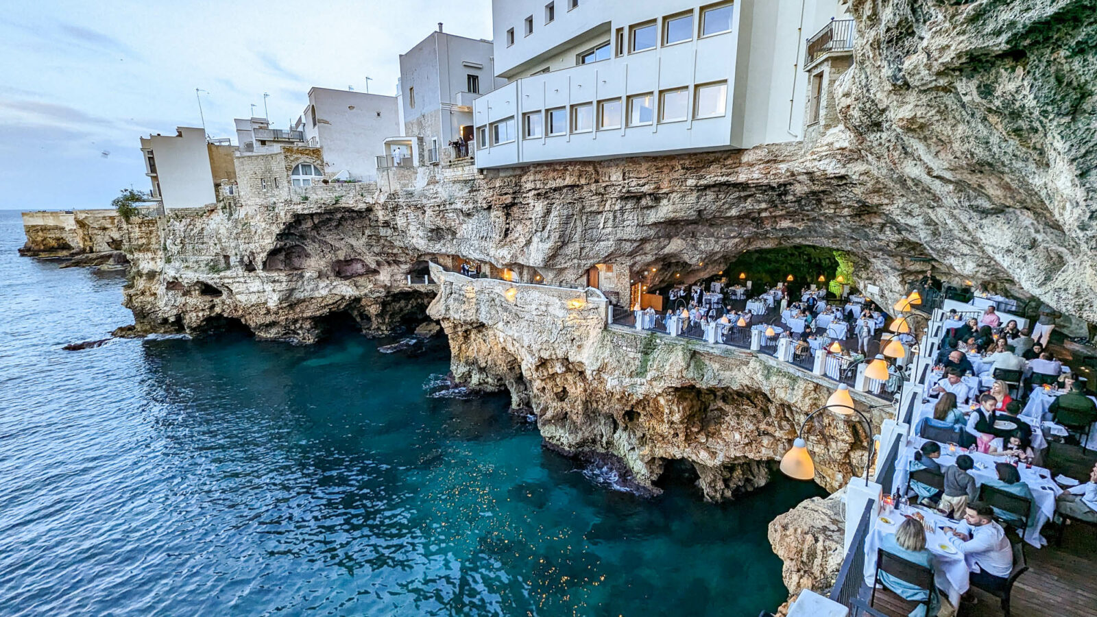 looking down on the tables and sea from above inside the cave during the day