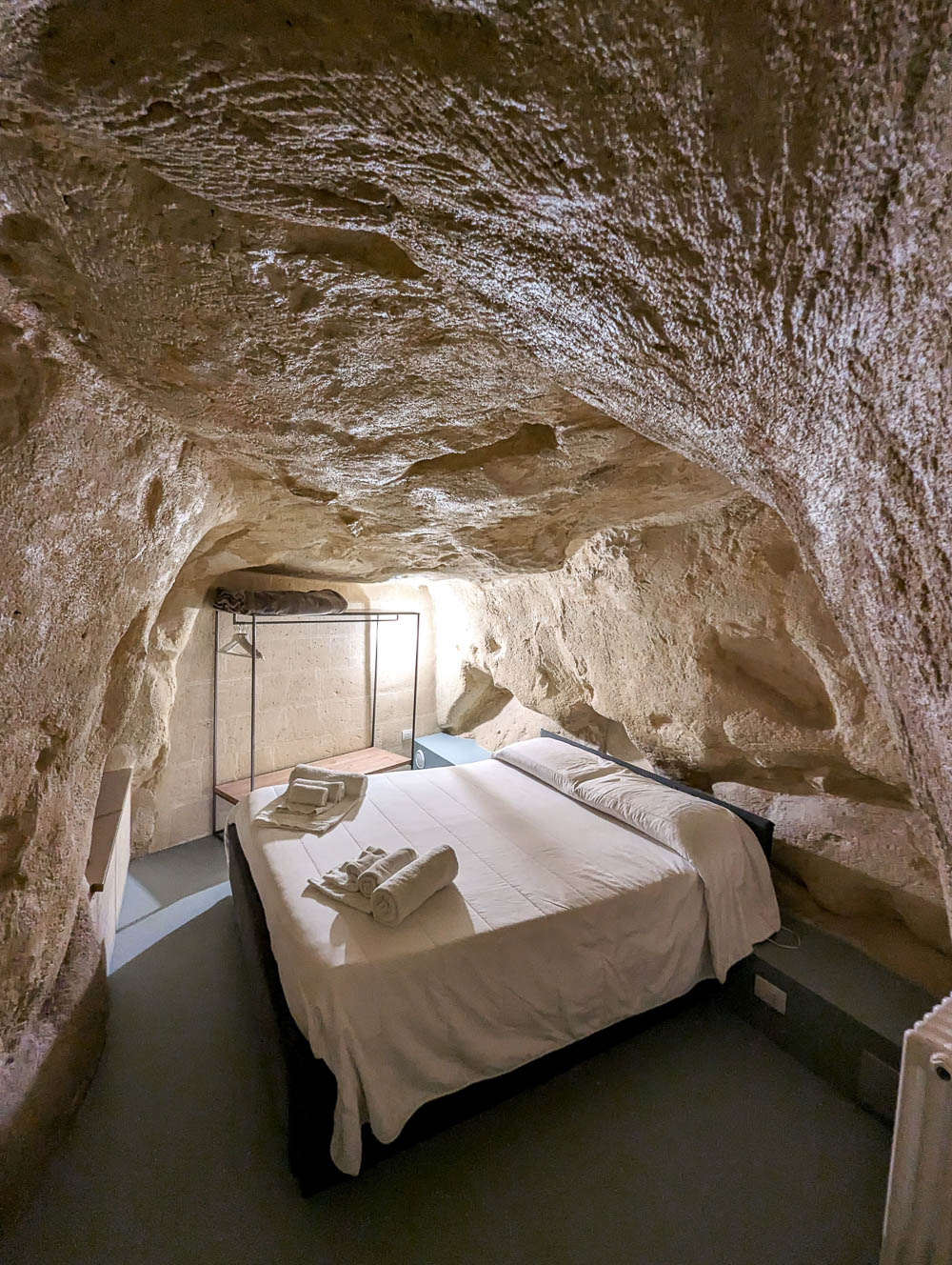 small beige cave room with a white bed inside