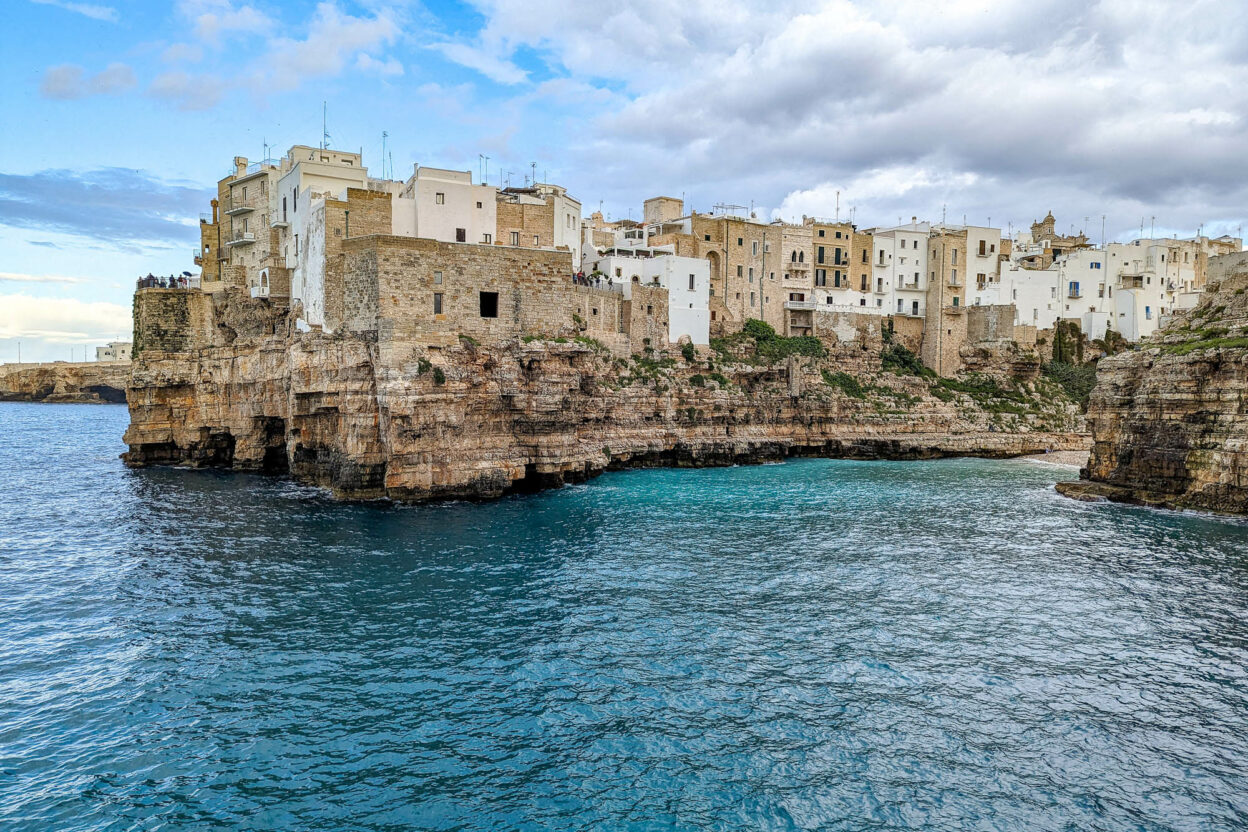 white and tan buildings on a cliff over a turquoise ocean