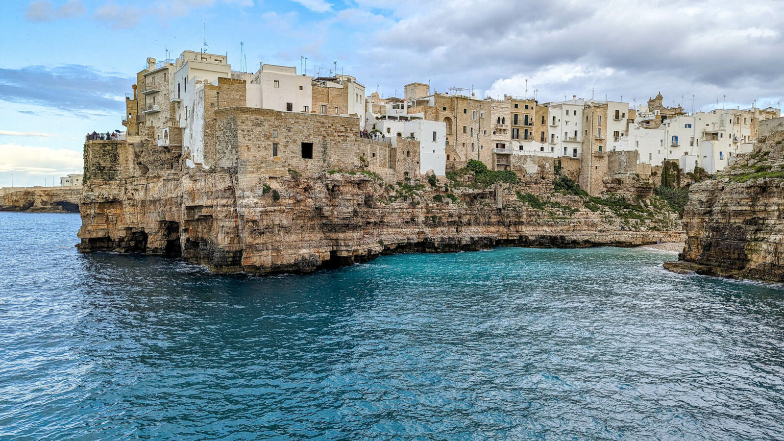 white and tan buildings on a cliff over a turquoise ocean